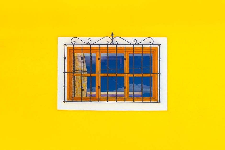 Yellow painted wall with a small framed window